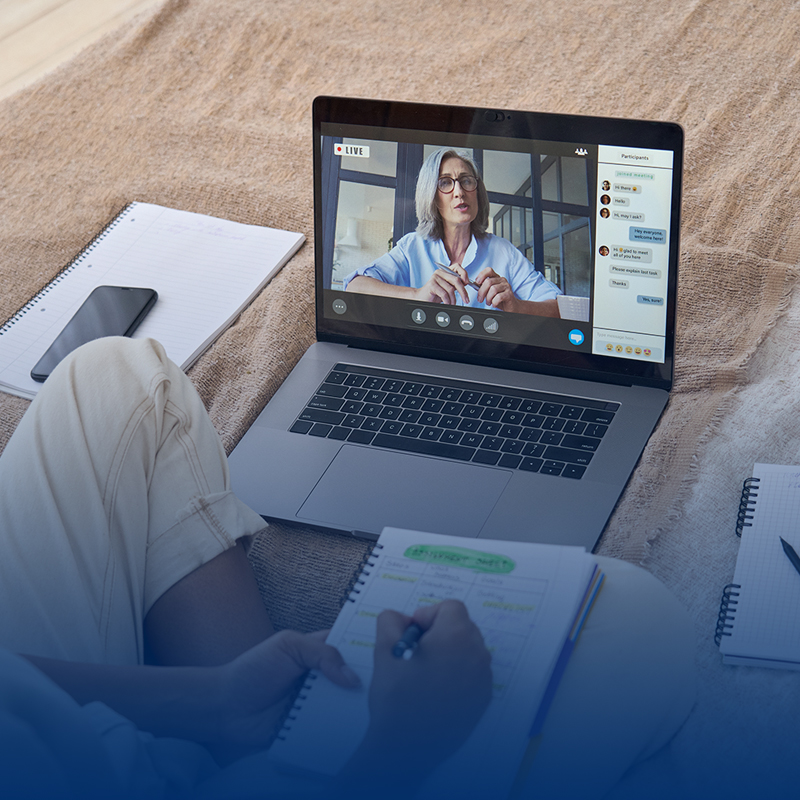 woman-sitting-on-floor-takes-notes-while-on-video-conference