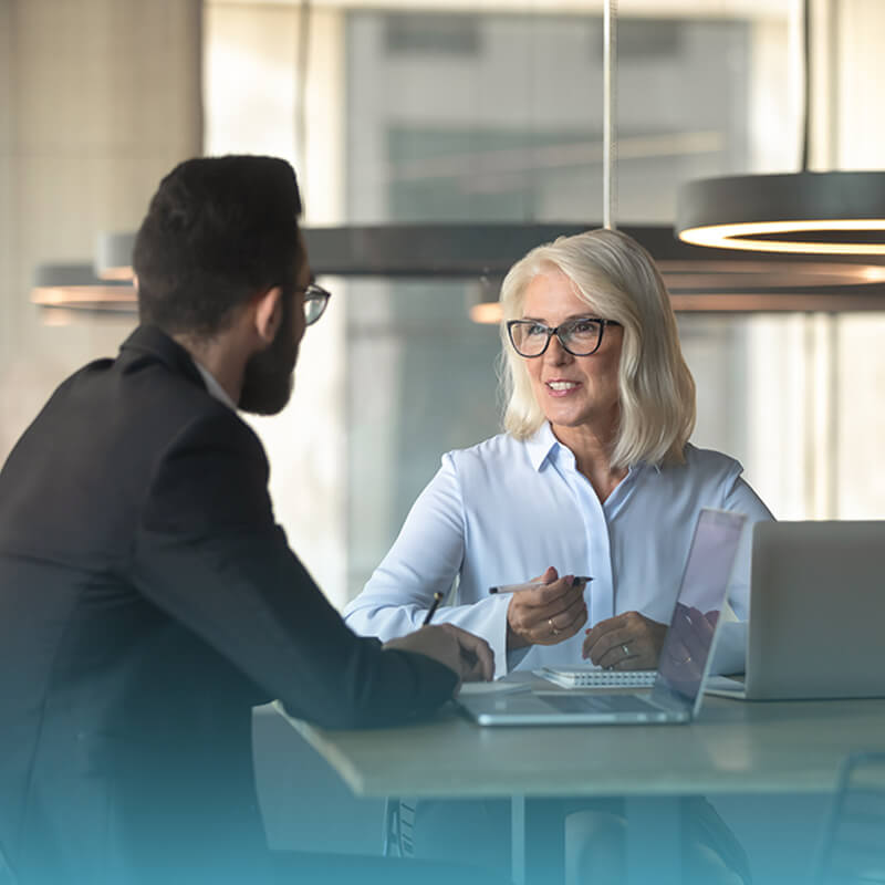 man-and-woman-sitting-at-table-having-conversation-in-sunlight-coach-approach-training-institute